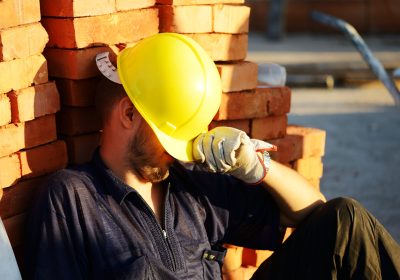 construction worker resting against bricks heat exhaustion